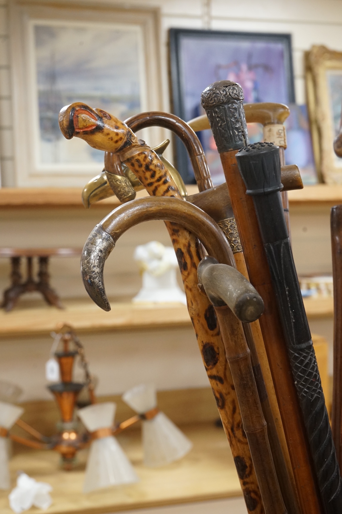 A collection of various walking sticks, some silver mounted, an umbrella with bamboo handle and a brass stick stand, stick stand 45cm high